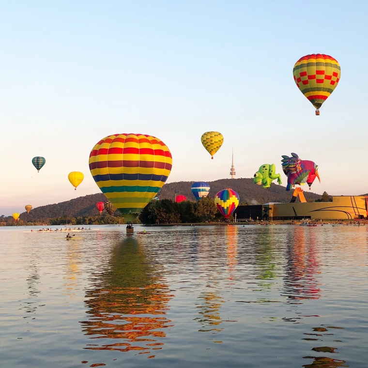 Balloons skimming water of Lake Burley Griffin during Canberra Balloon Spectacular